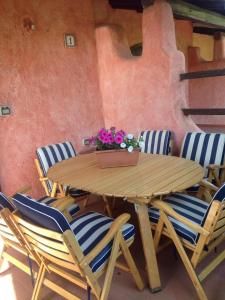 un tavolo e sedie in legno con fiori di Il Melograno Cannigione Villaggio Gallura a Cannigione