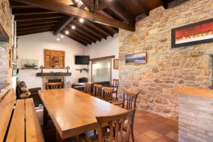 a dining room with a wooden table and a stone wall at Casa de Aldea con Piscina Calefactada opcional - CA-1451-AS in Villaviciosa