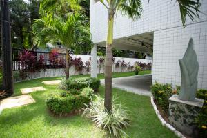 a garden with palm trees and plants in front of a building at FLAT BOA VIAGEM PRÓXIMO A PRAIA in Recife