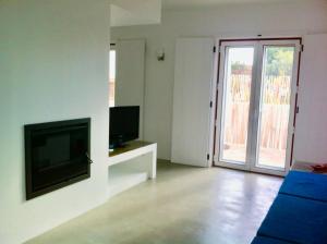 a living room with a flat screen tv and a living room with a door at Casa da Âncora - Comporta in Comporta