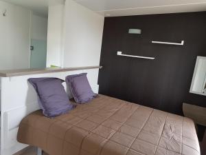 a bedroom with a bed with two purple pillows at Village Guerzaille in Saint-Caradec