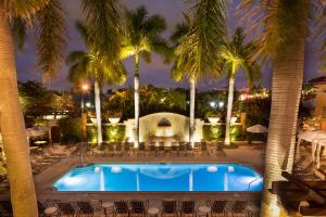 a pool with chairs and palm trees at night at Bellasera Resort in Naples