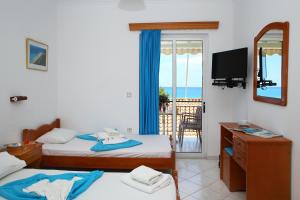 a bedroom with two beds and a television and a balcony at Kathisma Studios Apartments-Theochari Angeliki GP in Agios Nikitas