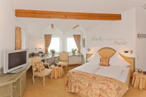 a bedroom with a bed and a tv and a desk at Malerwinkel Hotel in Bergisch Gladbach