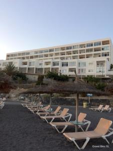 une rangée de chaises longues et un grand bâtiment dans l'établissement El Ancla - El Mar y La Playa, à Callao Salvaje