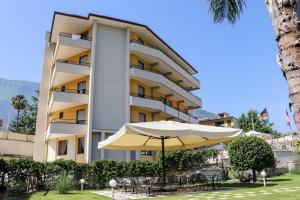 ein Hotel mit einem Sonnenschirm, Tischen und Stühlen in der Unterkunft Europa Stabia Hotel in Castellammare di Stabia