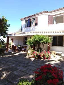 a white house with flowers in front of it at La Rucchetta - Alghero Villa e Depandance in Alghero