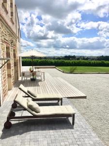 eine Terrasse mit 2 Liegestühlen und einem Sonnenschirm in der Unterkunft Galerie, Tumulus de la Hogue in Fontenay-le-Marmion