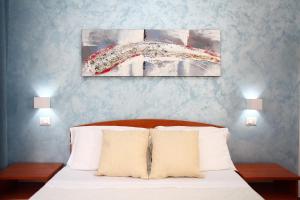 a bedroom with a bed and two paintings on the wall at Country Villa San Vito Bay in San Vito lo Capo