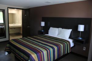 a hotel room with a bed with a striped blanket at Castle Inn East Greenbush Castleton-on-hudson in East Greenbush