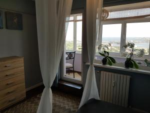 a bedroom with a window with curtains and a chair at Apartament Harbour View in Constanţa