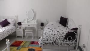 a white bedroom with a bed and a mirror at The Lodge Greatwood in Ipswich