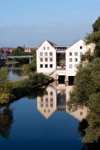 a large white building next to a river at SORAT Insel-Hotel Regensburg in Regensburg