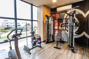 un gimnasio con cintas de correr y elípticas en una habitación con ventanas en ibis Palmas Avenida JK, en Palmas