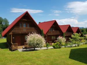 dos casas con techos rojos en un césped verde en Domki Nad Krystaliczną Zatoką en Polańczyk