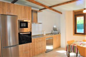 a kitchen with a stainless steel refrigerator and wooden cabinets at Casa Vazquez Sanxenxo La Lanzada in O Grove