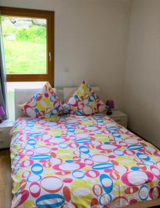 ein Bett mit farbenfroher Bettdecke in einem Schlafzimmer in der Unterkunft La Chaumière d'Hérens in Vernamiège