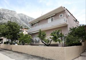 Un edificio rosa con árboles delante. en Apartmani Vinko, en Baška Voda