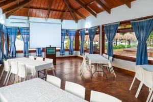 a room with white tables and chairs and a screen at Nanajuana Río Dulce in Rio Dulce