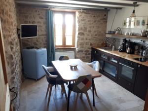 uma cozinha com mesa e cadeiras num quarto em La Pierre du Grain em Ravel