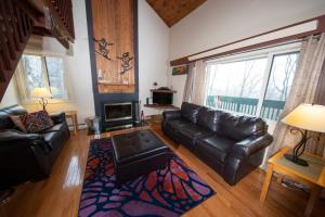 a living room with a leather couch and a fireplace at Okemo Mountain Lodging in Ludlow