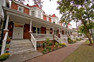 a red brick house with white porch and stairs at 420Waldburg A · Modern Apt with Southern Charm Blocks from Forsyth in Savannah