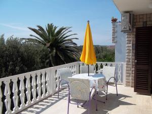 a table and chairs with a yellow umbrella on a balcony at Apartments Cavar in Rab