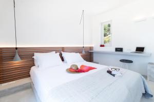 a bedroom with a white bed with a hat and sunglasses at Wabi Luxury Suites & Maisonettes Ios in Ios Chora