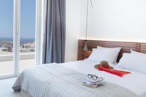 a bed with a teddy bear and a pair of glasses on it at Wabi Luxury Suites & Maisonettes Ios in Ios Chora