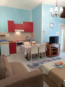 salon ze stołem oraz kuchnia z czerwonymi szafkami w obiekcie Apartmani Jovanovic w Petrovacu na Moru