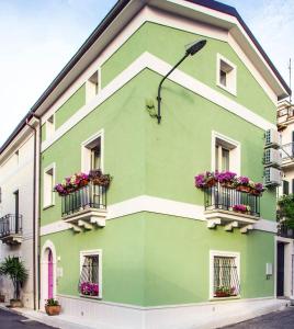 a green building with flowers on the balconies at B&B La Mia Valigia in San Lucido