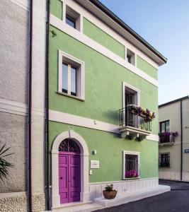 a green building with a purple door and a balcony at B&B La Mia Valigia in San Lucido