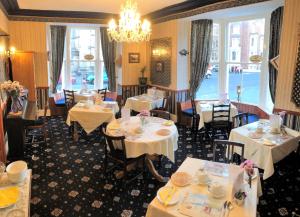 a restaurant with white tables and chairs and a chandelier at The Captain's Lodge accommodation in Whitby