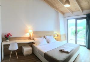 1 dormitorio con 1 cama, escritorio y ventana en First House, en Himare