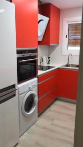 cocina con armarios rojos y lavadora en Apartament L'Alba 2, en Tossa de Mar