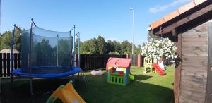 um quintal com um parque infantil com um trampolim em Apartamenty Kalinowa em Rowy