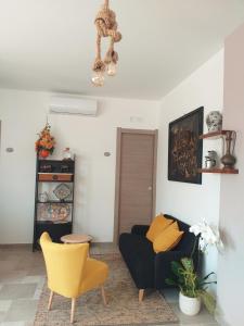 ein Wohnzimmer mit einem schwarzen Sofa und einem gelben Stuhl in der Unterkunft B&B Marsà in Marzamemi