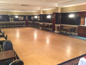 a dance hall with a wooden floor and chairs at Kensington Hotel in Llandudno