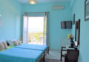 Habitación azul con 2 camas y balcón. en Hotel Perama en Perama