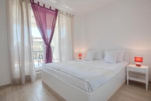 a white bedroom with a large bed and a window at Guest House Djonovic in Petrovac na Moru