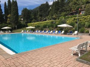 una gran piscina azul con sillas y sombrillas en Residenza del Pascià - Appartamento Camphora, en Oggebbio