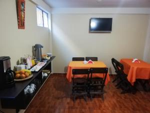 una habitación con 2 mesas y una mesa con mantel naranja en Killa Sumak, en Machu Picchu
