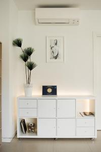 - une commode blanche dans une pièce blanche avec une plante dans l'établissement Villa Magnolia, à Torri del Benaco