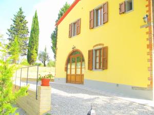 a yellow house with a door and a fence at Agriturismo Martignana Alta in Empoli