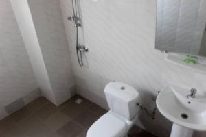 a white bathroom with a toilet and a sink at Hotel Eucalyptus Anan in Bingerville