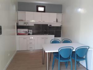 a kitchen with a white table and blue chairs at Chambre d'hôte les vacanciers in Nianing