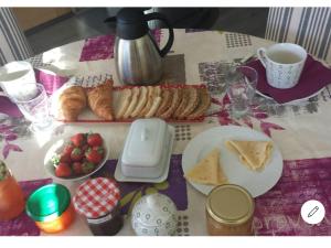 un tavolo con colazione a base di croissant, pane e frutta di Le petit Ventoux a Malaucène