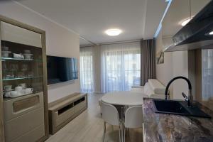 a kitchen with a sink and a table in a room at Gardenia Sea Side MARTINA 1 Dziwnów in Dziwnów