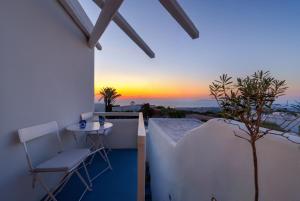 balcón con mesa, sillas y puesta de sol en Christina's Cave House en Fira