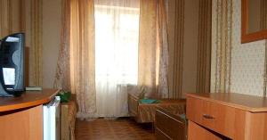 a room with a television and a window with curtains at Пансионат Химик in Novomikhaylovskiy